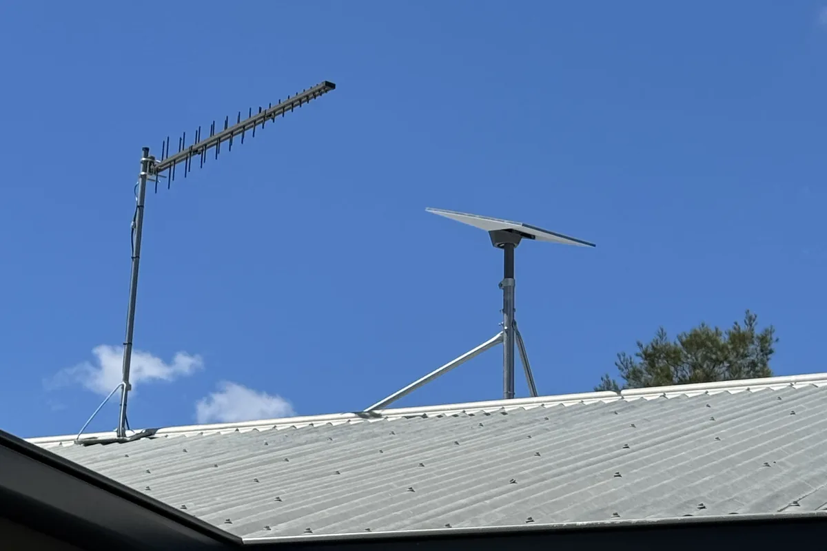 A Starlink dish and yagi antenna mounted together on a roofline